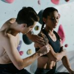 Two climbers prepare with athletic tape before tackling an indoor climbing wall.