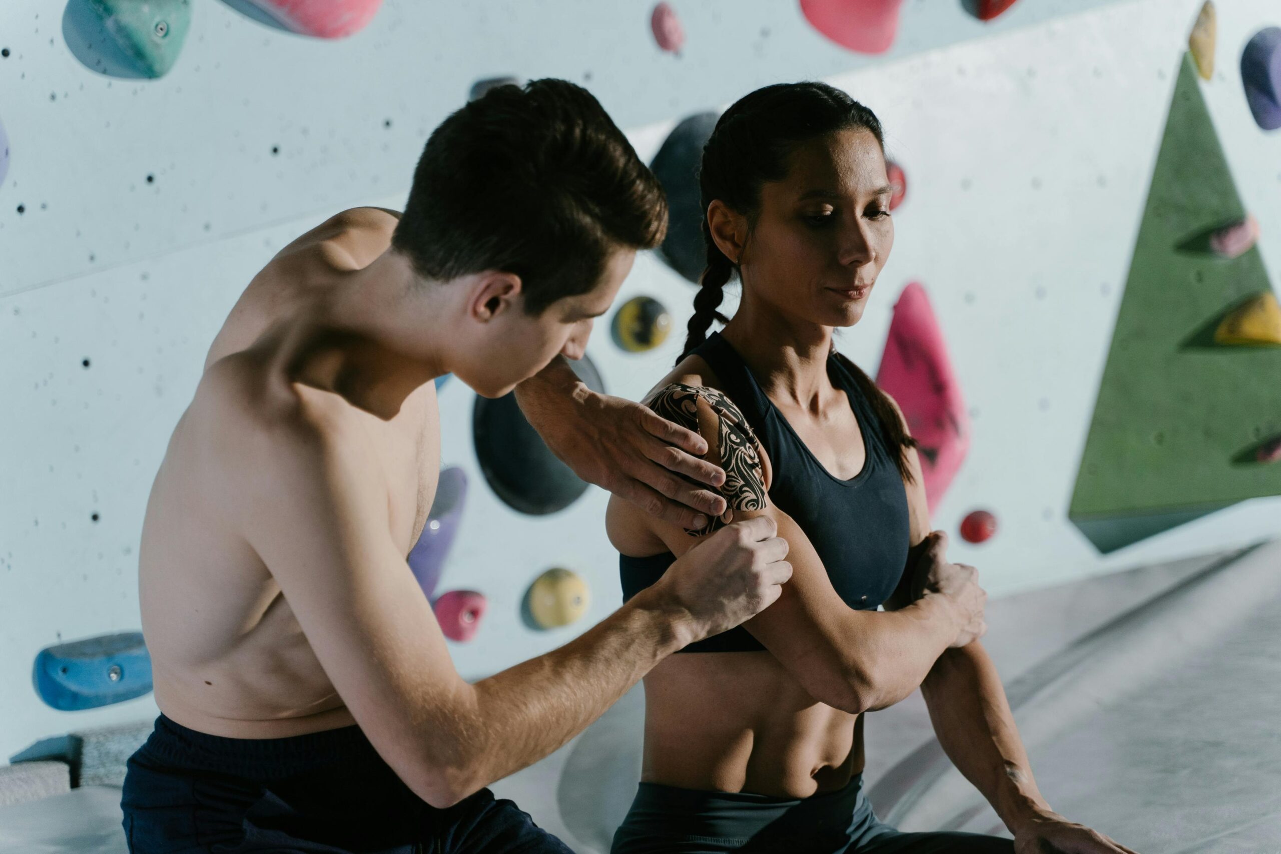 Two climbers prepare with athletic tape before tackling an indoor climbing wall.